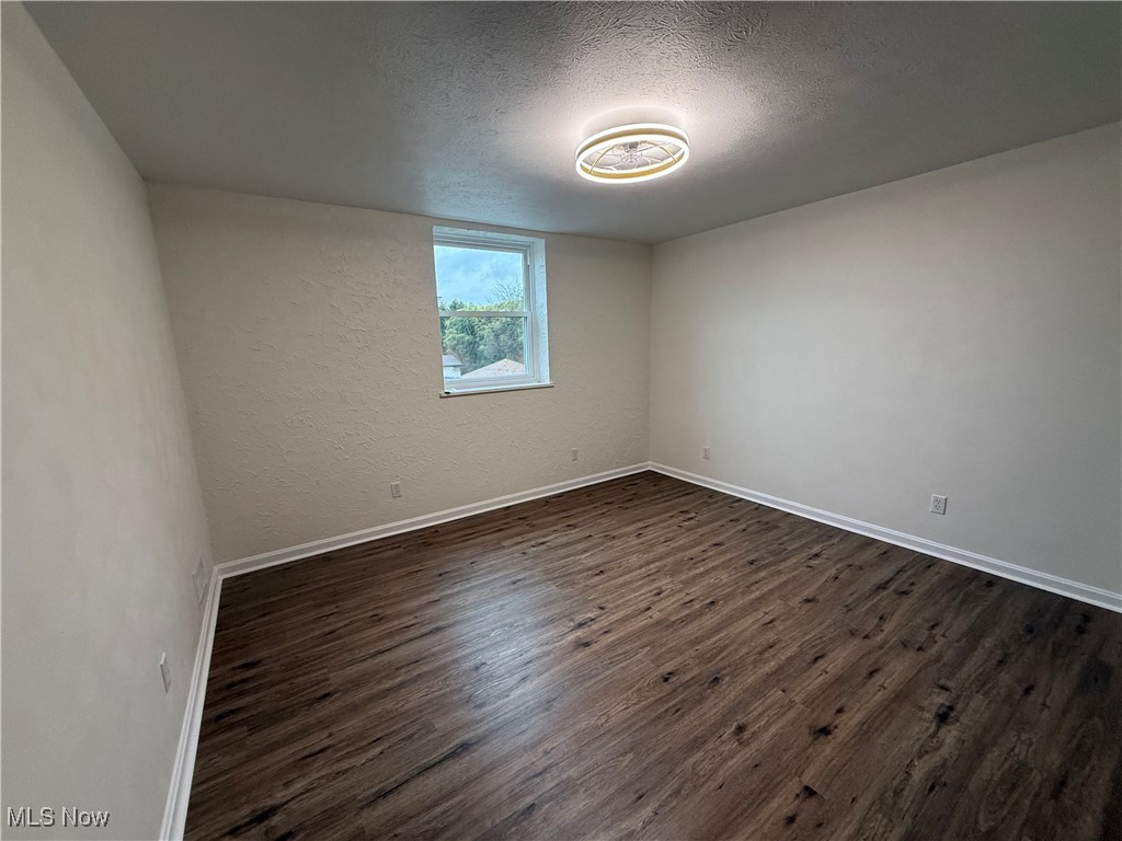 522 North 3rd Street Toronto, OH 43964 - Photo 31 of 47 Spare room with a textured ceiling, dark wood-type flooring, and a textured wall