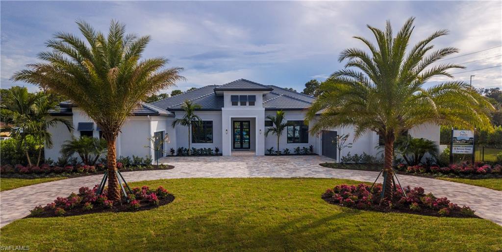 a front view of a house with garden and tree