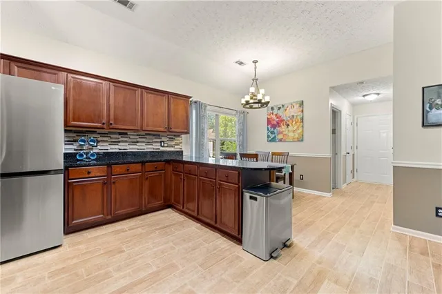 a kitchen with stainless steel appliances granite countertop a stove a refrigerator and a wooden cabinets