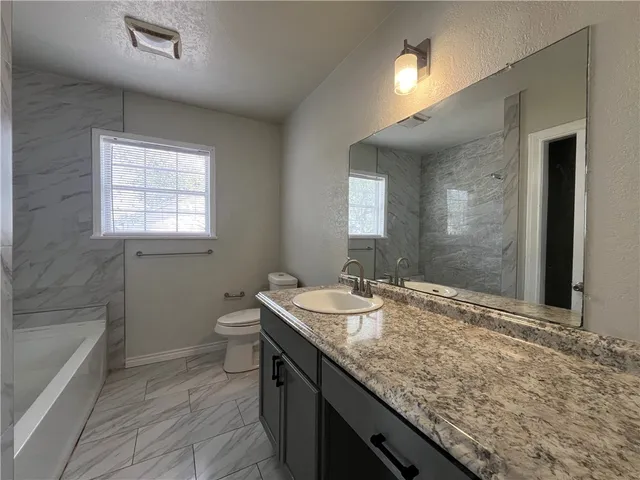 a bathroom with a granite countertop sink a toilet and shower