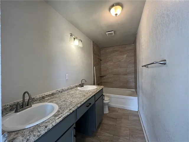 a spacious bathroom with a granite countertop sink toilet and shower