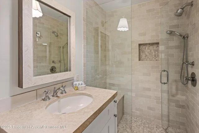 a bathroom with a granite countertop sink a mirror and shower