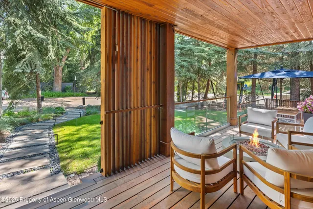a view of a patio with table and chairs potted plants with wooden floor and fence