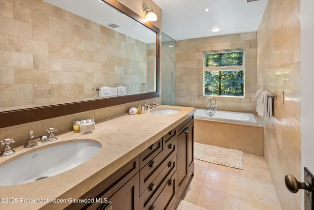 a spacious bathroom with a tub sink and mirror