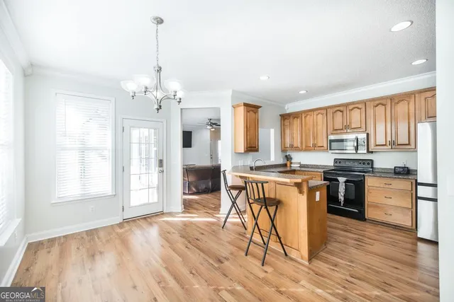 a kitchen with stainless steel appliances granite countertop a stove top oven a sink dishwasher and a refrigerator with wooden floor