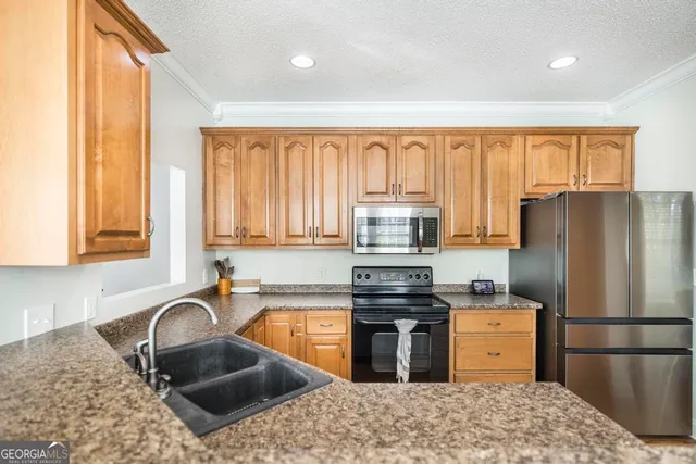 a kitchen with granite countertop a stove a sink and a refrigerator