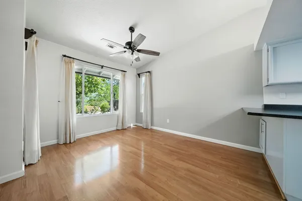 a view of empty room with wooden floor and fan