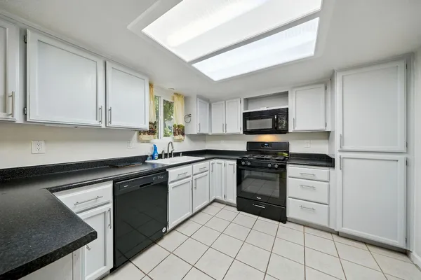 a kitchen with granite countertop white cabinets and stainless steel appliances
