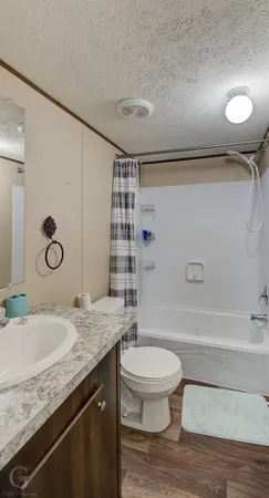 a bathroom with a granite countertop sink a toilet a mirror and shower