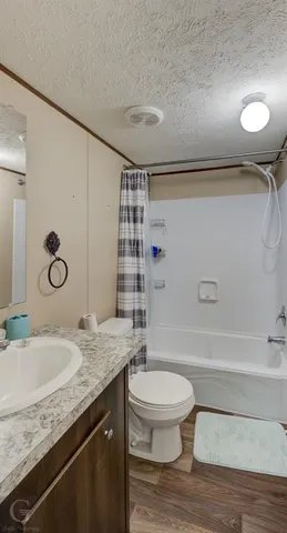 a bathroom with a granite countertop sink a toilet a mirror and shower