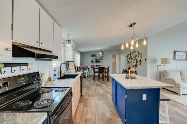 a kitchen with a stove a sink dishwasher and a dining table with wooden floor