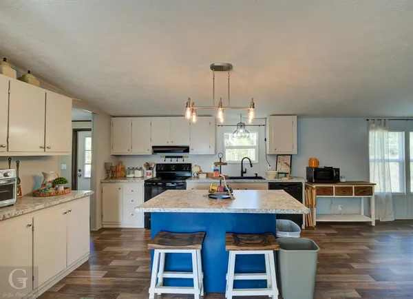 a kitchen with a refrigerator a stove a sink dishwasher and white cabinets with wooden floor