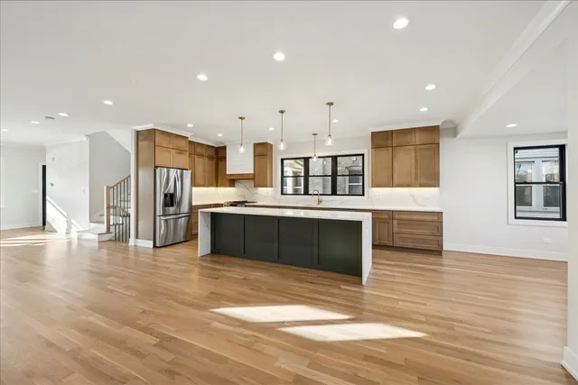 a large kitchen with stainless steel appliances a large counter top a refrigerator and a sink