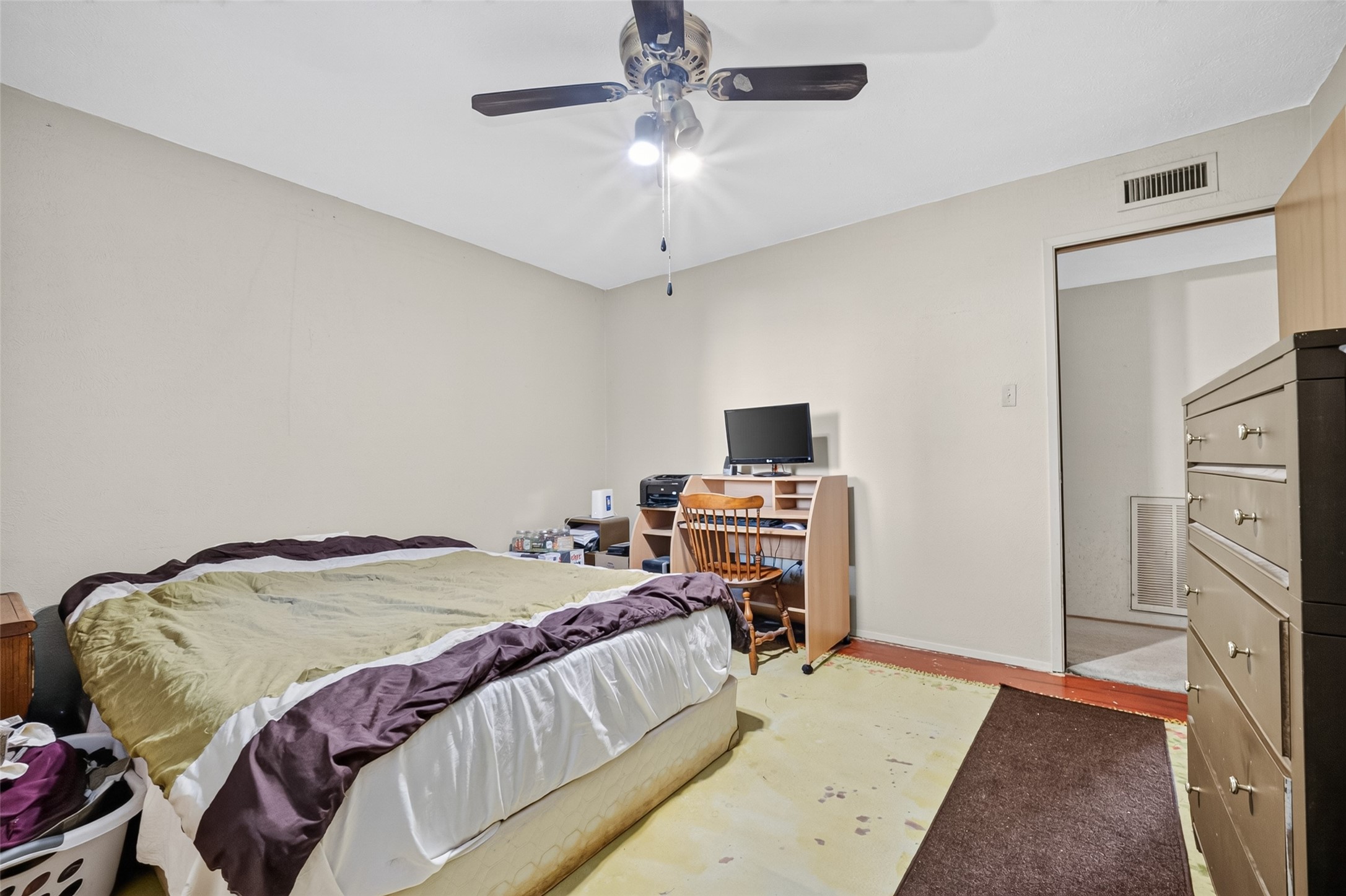22926 Millgate Drive Spring, TX 77373 - Photo 18 of 34 This bedroom features neutral walls, a ceiling fan, and ample natural light. It includes a bed, a small office setup, and a dresser, offering a cozy and functional space.