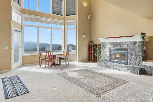 2887 View Crest Circle North Logan, UT 84341 - Photo 13 of 37 Living room featuring a fireplace, carpet flooring, a mountain view, and a high ceiling