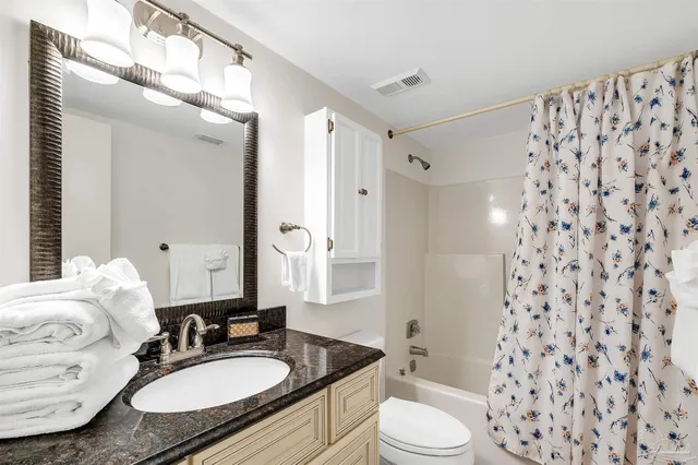 a bathroom with a granite countertop sink toilet a mirror a vanity and shower