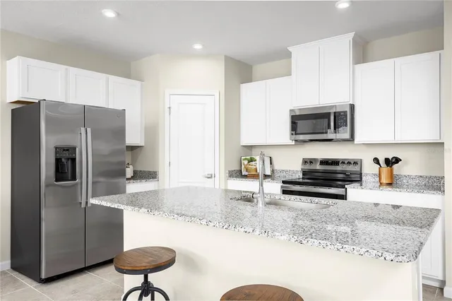 a kitchen with stainless steel appliances granite countertop a refrigerator a stove a sink a stove a dining table and chairs