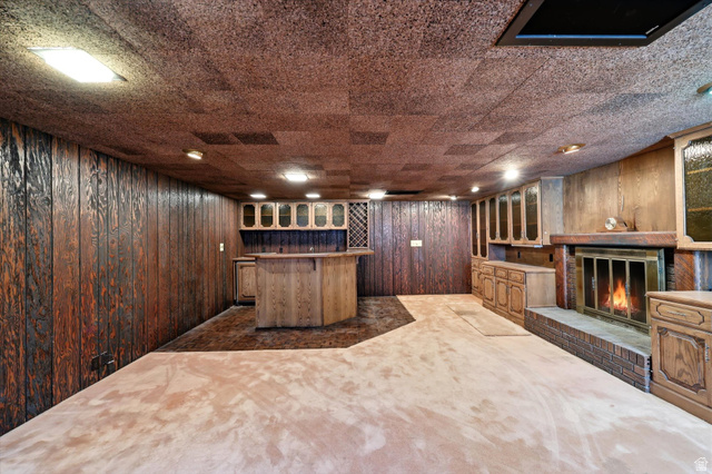 292 West 400 South Springville, UT 84663 - Photo 34 of 37 Spacious room featuring wood paneling, built-in wet bar with cabinetry and wine rack, brick-surround fireplace, and light-toned carpet flooring