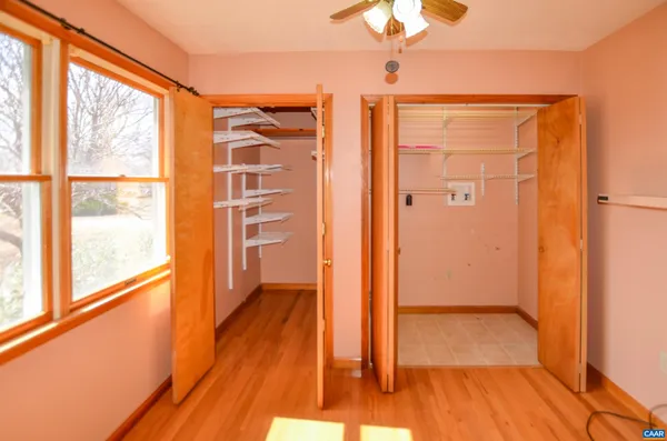 a view of empty room with wooden floor and fan
