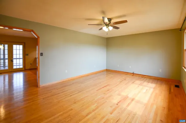 an empty room with wooden floor fan and windows