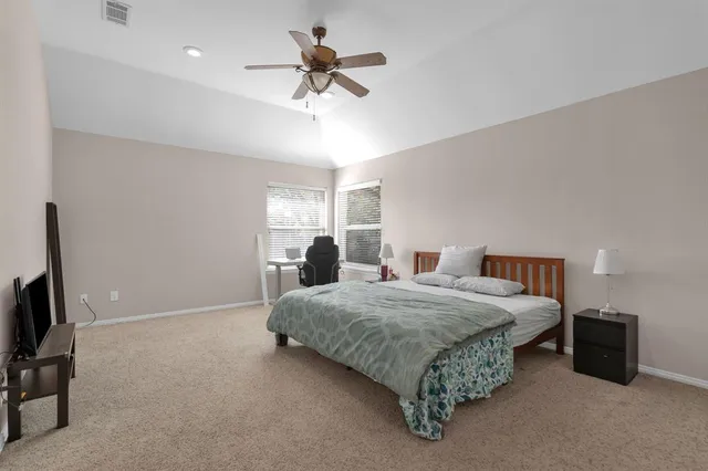 a bedroom with a bed a couch and a ceiling fan