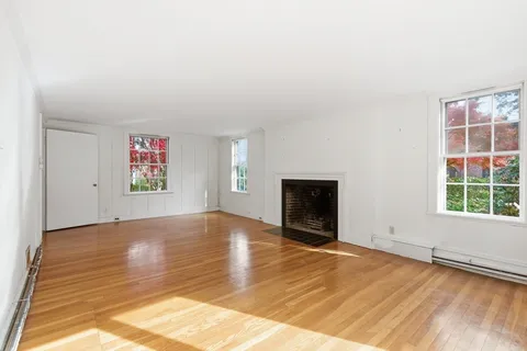 an empty room with windows and fireplace