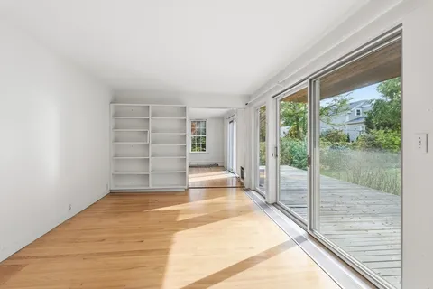 a view of empty room with wooden floor and floor to ceiling window
