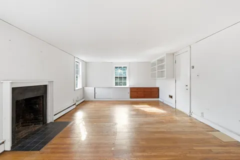 a view of empty room with wooden floor and fireplace