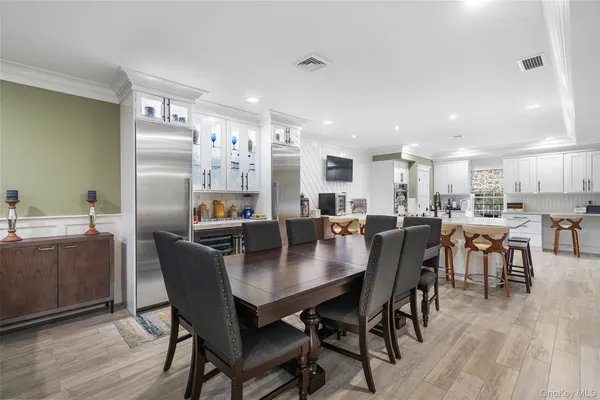 a dining room with kitchen island a dining table wooden floor and a kitchen view