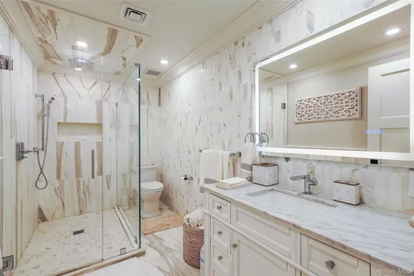 a bathroom with a granite countertop sink a toilet and shower