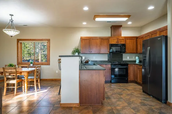 a kitchen with stainless steel appliances a refrigerator a stove a sink a dining table and chairs with wooden floor