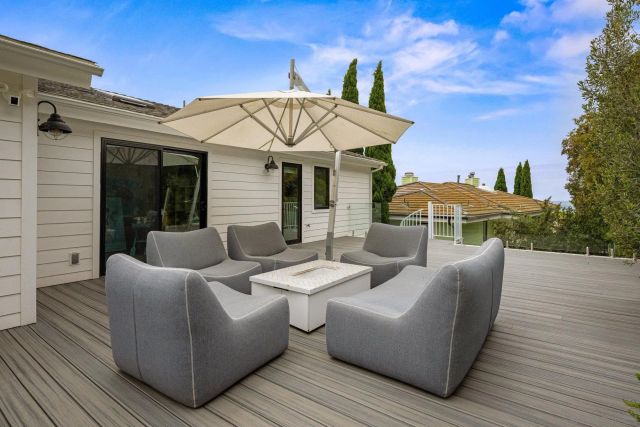 a view of a patio with couches table and chairs under an umbrella with wooden floor