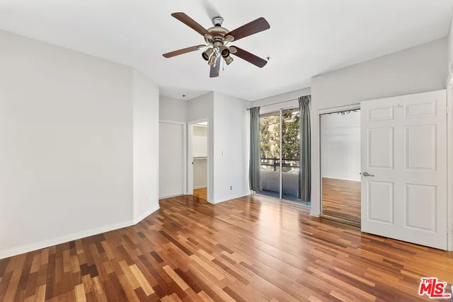 a view of empty room with wooden floor and fan