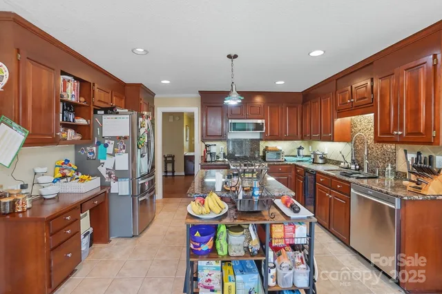 a kitchen with stainless steel appliances granite countertop a refrigerator a stove top oven and a sink
