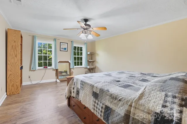 a bed sitting in a spacious bedroom next to a window and a chandelier