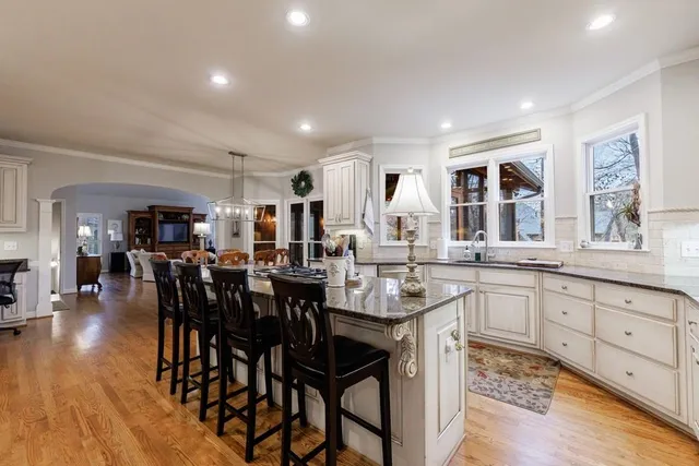 a kitchen with stainless steel appliances granite countertop a stove top oven a sink a dining table and chairs with wooden floor