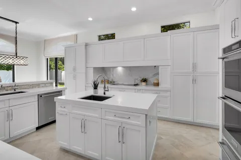 a kitchen with white cabinets and sink