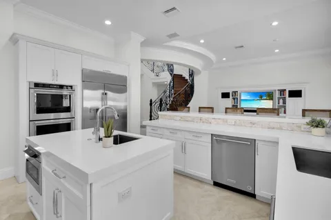 a kitchen with stainless steel appliances a sink a stove a microwave a center island and chairs