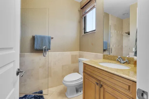 a bathroom with a granite countertop sink toilet a mirror and shower