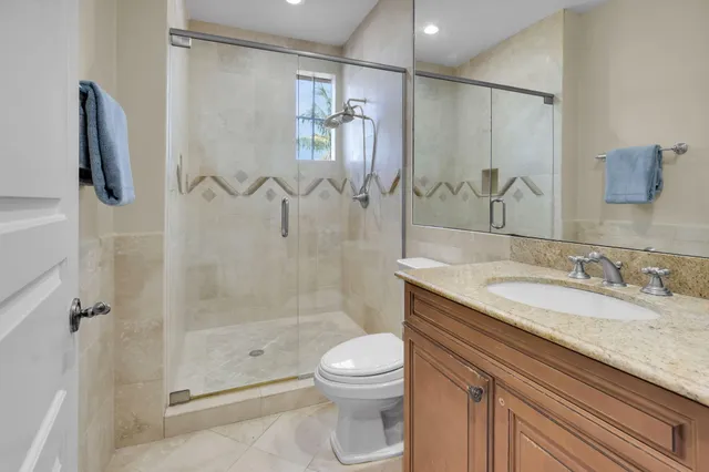 a bathroom with a granite countertop sink a toilet and shower