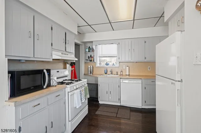 a kitchen with white cabinets and window