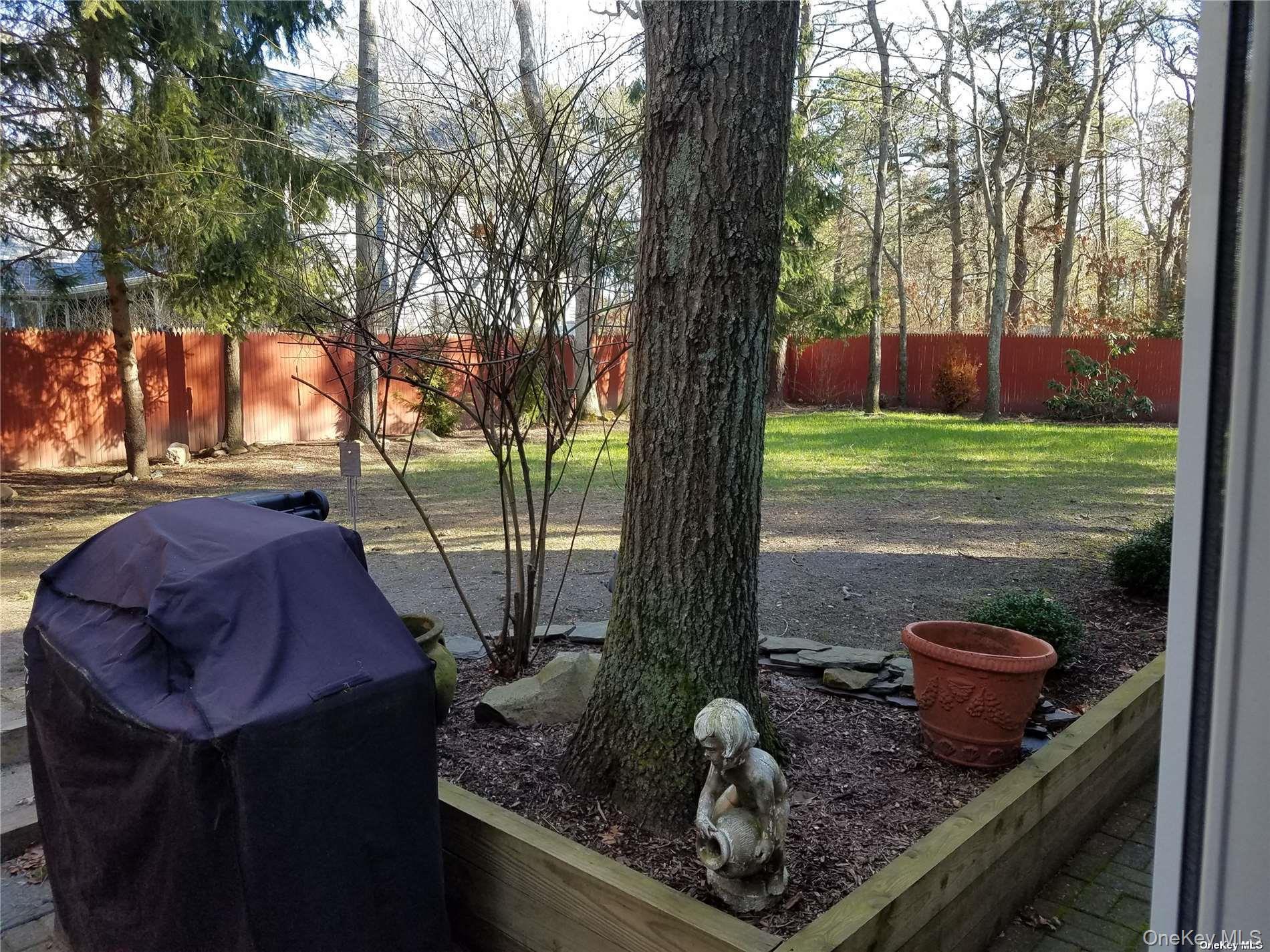 73 Spinney Road East Quogue, NY 11942 - Photo 19 of 20 a view of a backyard with table and chairs potted plants and a large tree