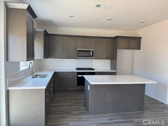 a kitchen with kitchen island stainless steel appliances a sink and a refrigerator