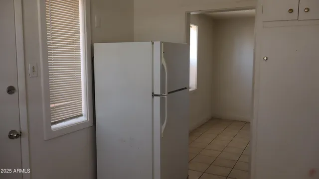 a view of a refrigerator in kitchen and a window in an empty room