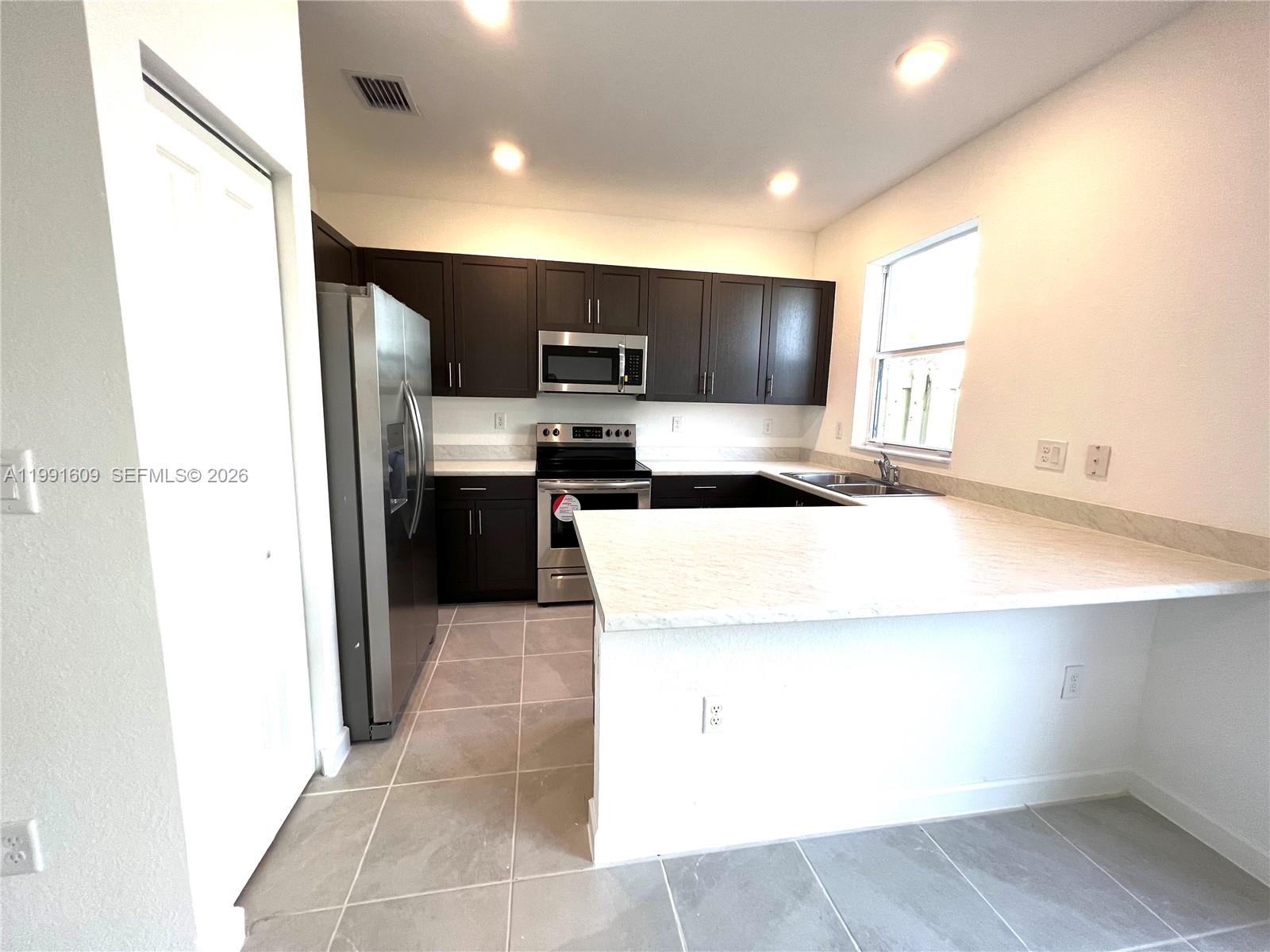 1864 Southeast 27th Street, Unit 1864 Homestead, FL 33035 - Photo 3 of 17 a kitchen with kitchen island stainless steel appliances a sink and a counter top space
