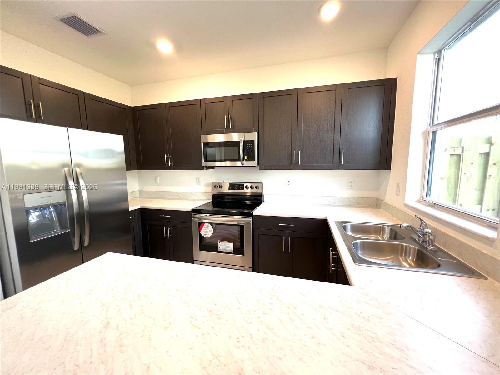 1864 Southeast 27th Street, Unit 1864 Homestead, FL 33035 - Photo 4 of 17 a kitchen with granite countertop a refrigerator and a sink