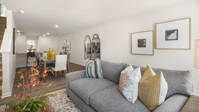 a living room with furniture and a dining table next to a window