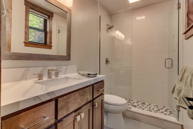 a bathroom with a sink a toilet a shower and a mirror