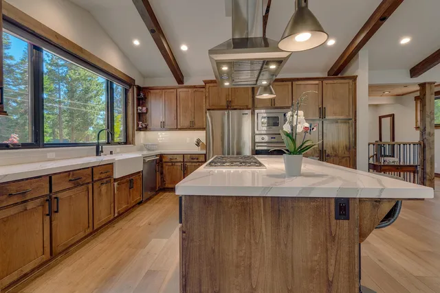 a kitchen with kitchen island a large counter top space a sink stainless steel appliances and windows