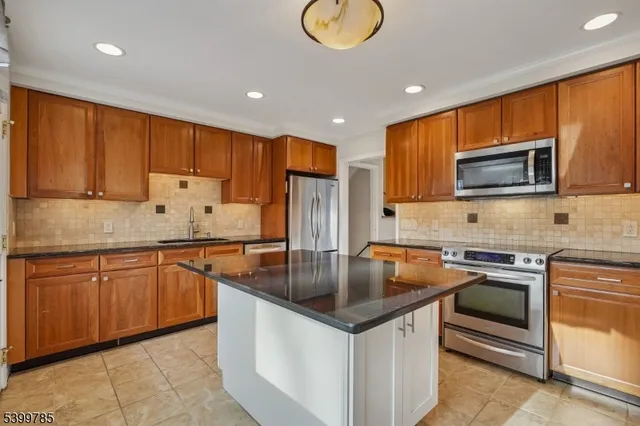 a kitchen with stainless steel appliances granite countertop a sink stove microwave and refrigerator